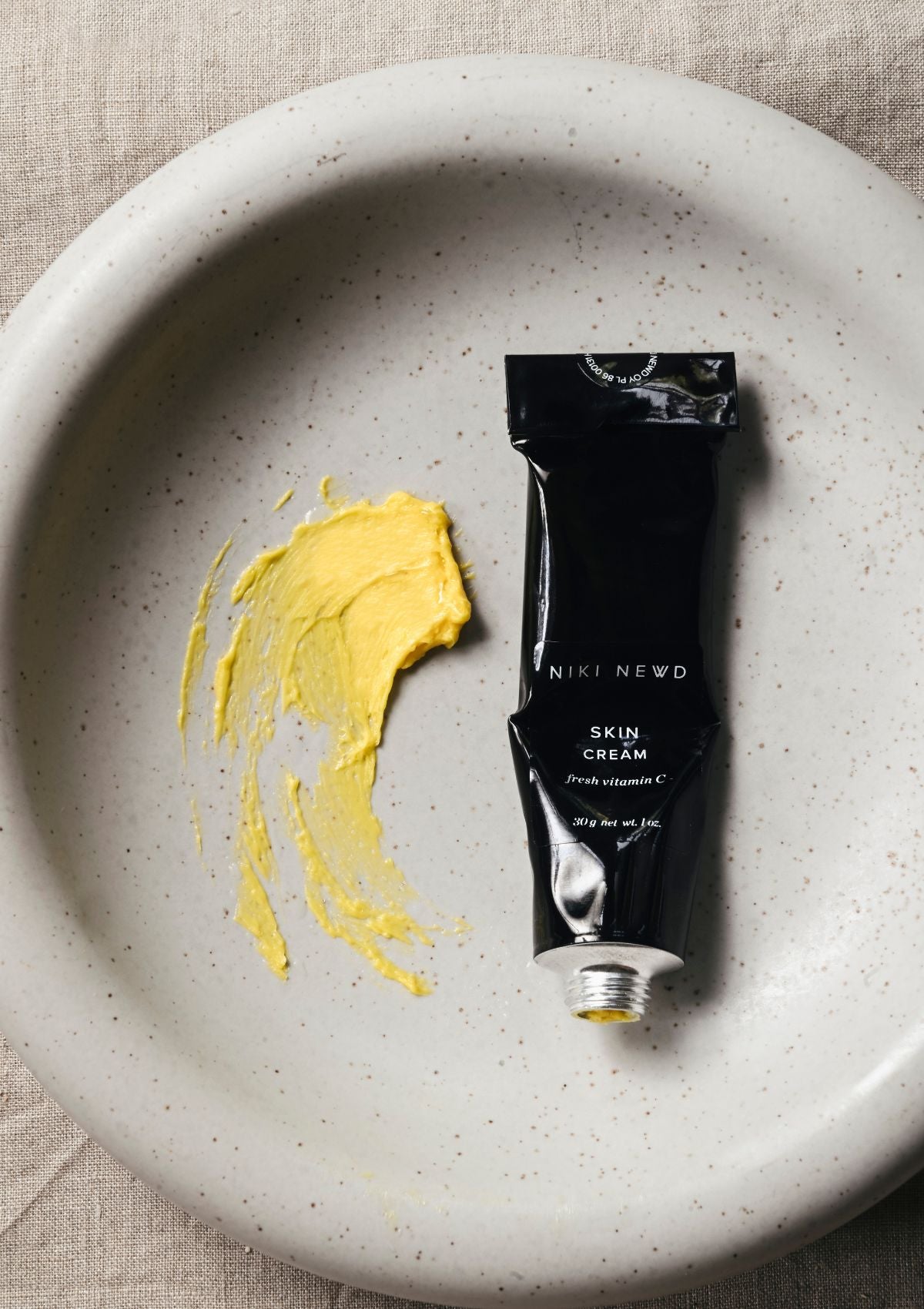 Niki Newd® Vitamin C Anti-Age Cream – tube and swatch of a rich, silky face cream with a luxurious texture that nourishes and visibly supports a firmer, more radiant-looking complexion.