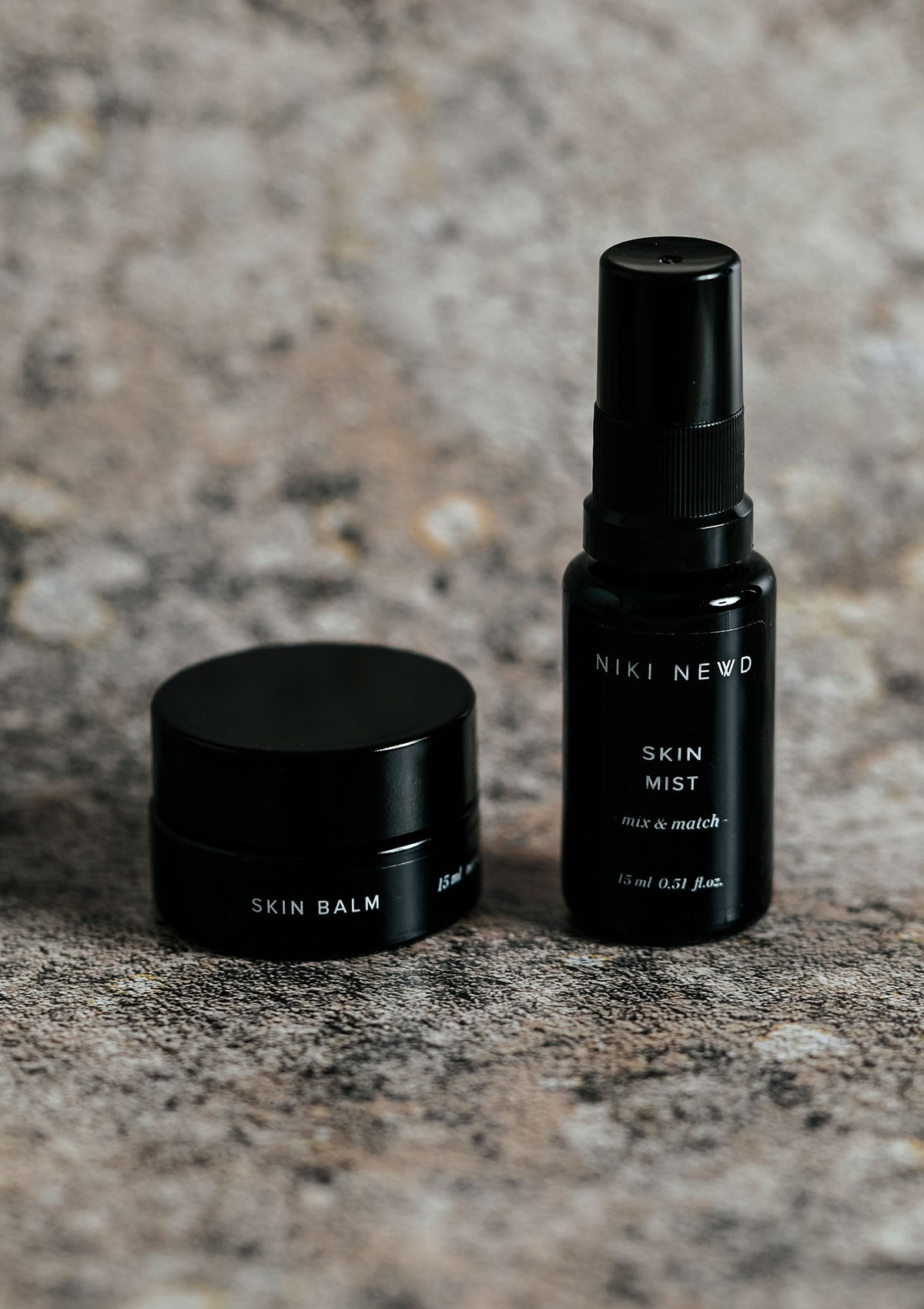 Niki Newd® Skin Balm – nourishing age and blemish defense balm shown with a hydrating facial mist for balanced, healthy-looking skin.