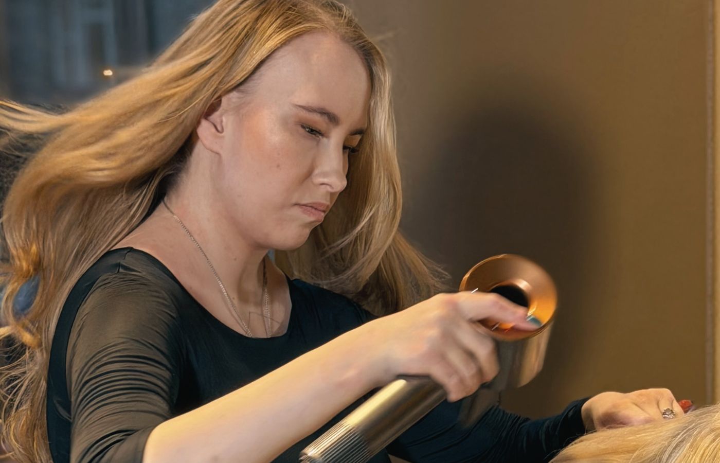 Niki Newd Studion ammattilainen hoitamassa asiakkaan hiuksia tunnelmallisessa boutique-salongissa.